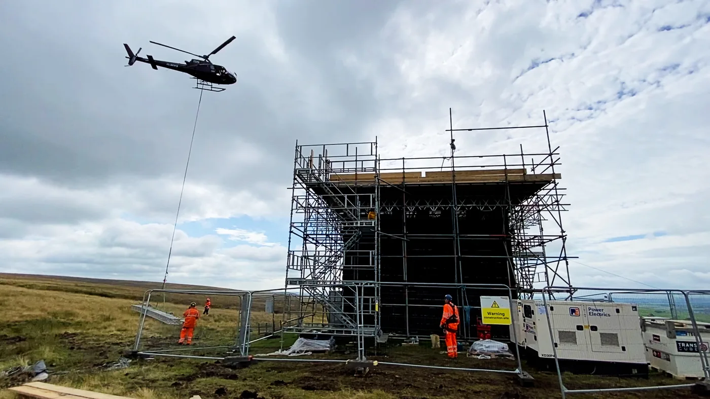 Helicopter lifting scaffold materials to a tunnel ventilation shaft scaffold on open moorland