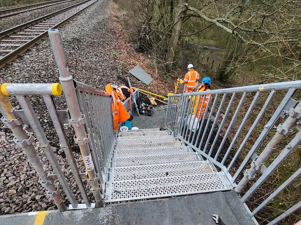 QED operatives at the top of an access stair beside the running line