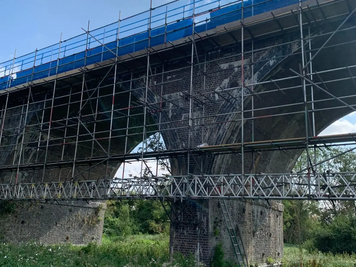 Viaduct parapet scaffold sitting on Apollo beams carried by CL25 brackets, with the flood arches left clear